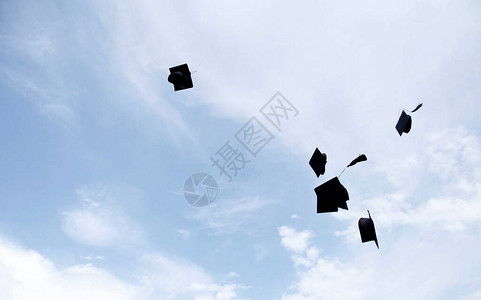 在蓝天背景下扔在空中的毕业帽背景图片