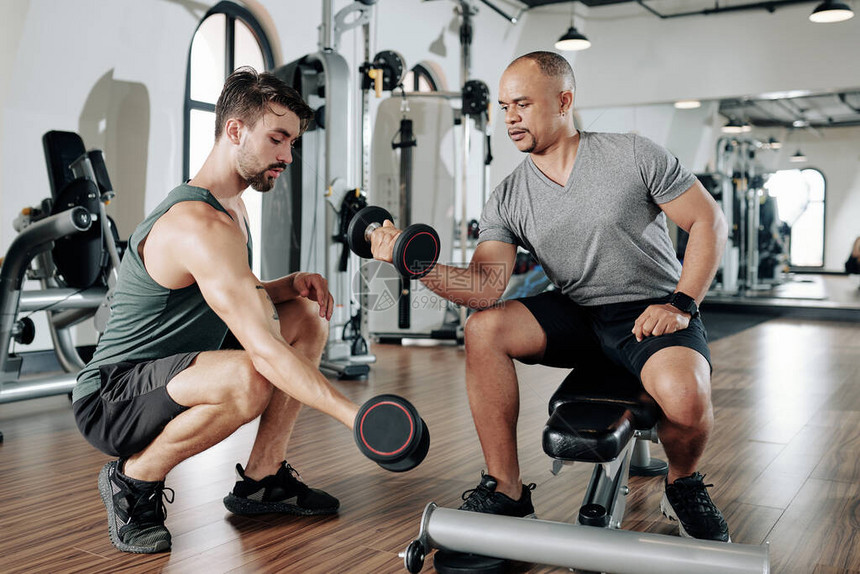 健身训练教向客户展示如何在肌肉上做二头图片
