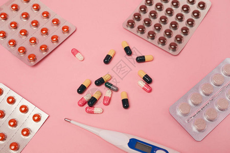粉红背景covid和流感概念的药胶囊药丸和温度计图片