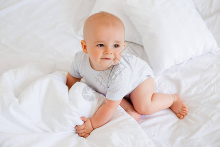 6个月身穿白体装躺在床上的男孩图片