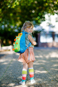 可爱的小可爱蹒跚学步的女孩在她去幼儿园的第一天健康美丽的婴儿步行到幼儿园学前班和幼儿园在城市街道上背着包的快乐背景图片