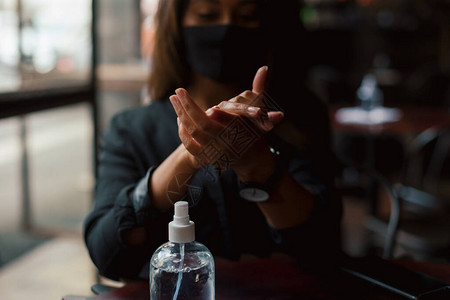 使用消毒剂洗手的年轻女子图片