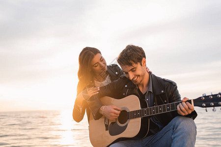女人拥抱男友的拥抱男朋友在海边弹声音吉他图片