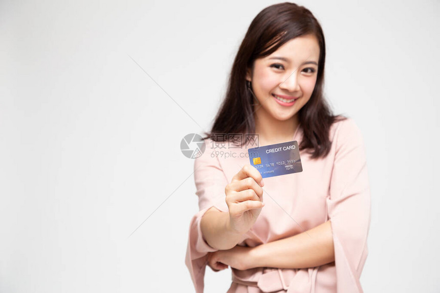 一位快乐的亚洲女手持自动取款机或借记卡或信用卡并用于网上购物的肖像图片