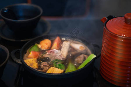 日本Sukiyaki猪肉牛肉和混合蔬菜在传统铸铁锅黑汤图片