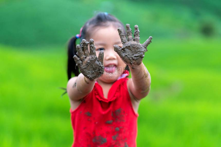 在户外玩的女孩举着肮脏的泥巴