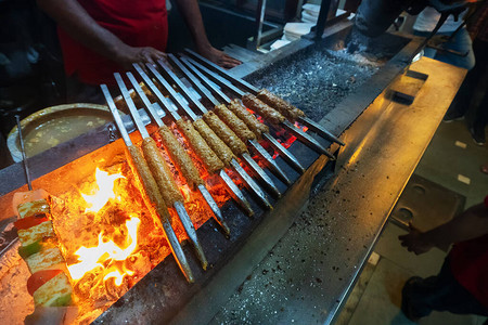 辛辣的鸡肉烤串正在用金属串烧烤图片