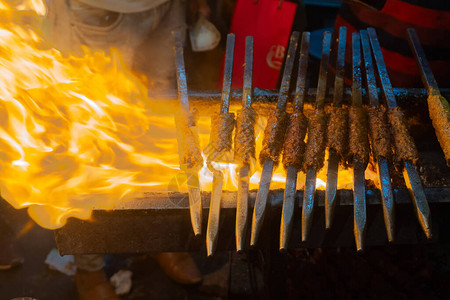 辛辣的鸡肉烤串正在用金属串烧烤图片