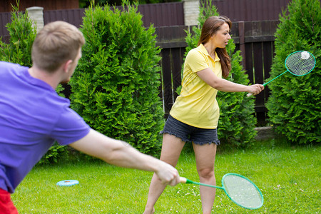 快乐的白种人夫妇在绿色背景上用球拍和羽毛球打羽毛球羽毛球业余比赛户图片