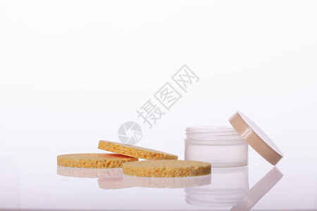 化妆品奶油罐和三个弹米色圆形海绵垫图片
