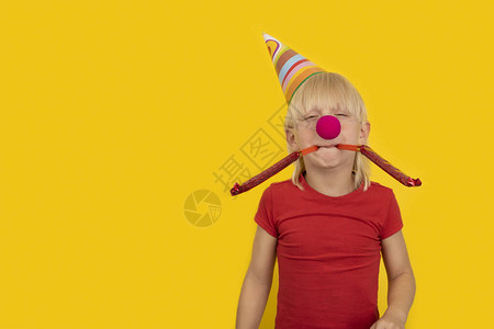 男孩吹在节日口哨中儿童与小丑鼻子图片