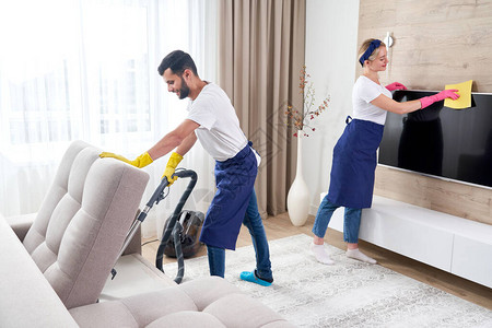 专业清洁工在公寓客厅里清洗地板和擦拭家具上的灰尘图片