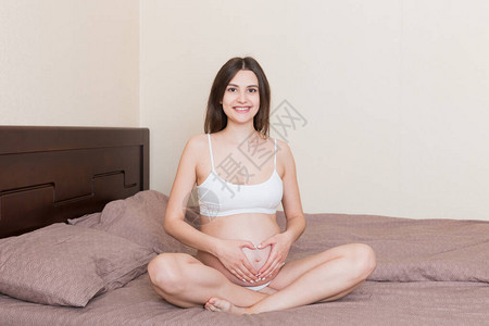 怀孕爱和期待概念在床上在家里做心事的孕背景图片
