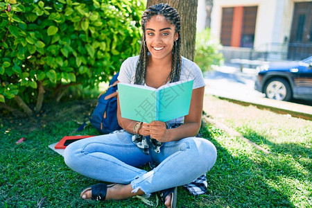 年轻非洲女学生在大学校园的草地上看书图片