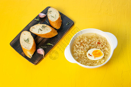 黄色背景的鸡蛋面木板上的面包和大蒜图片