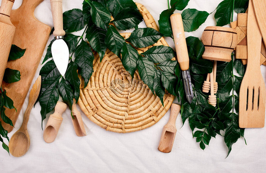 平铺有带绿叶的木制厨房用具纺织背景的烹饪工具烹饪博客和课程概念从上方捕获的ktchenware收藏图片