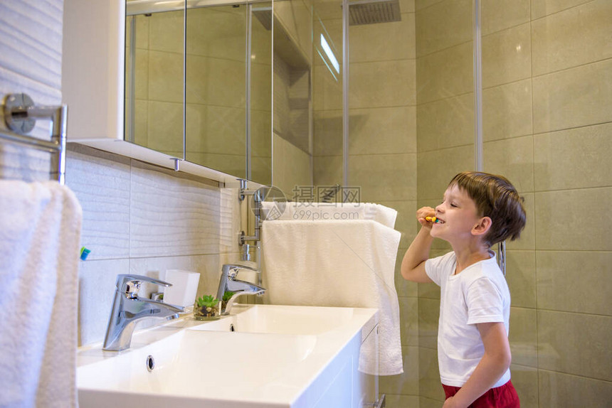 一个可爱的小男孩正在用牙刷牙在他穿着的纯白色T恤上图片