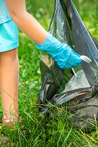 儿童从公园垃圾袋中扔垃圾的草地上收集图片