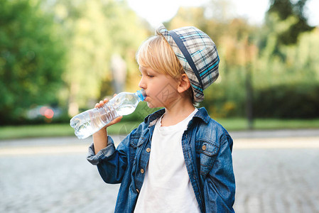 可爱的小男孩从塑料瓶里喝水孩子在户外喝水孩子在街上喝矿泉水图片