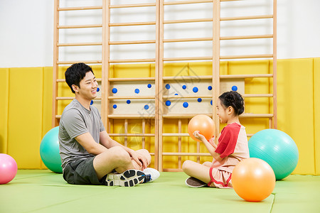 教练带小女孩一起玩抛球游戏图片