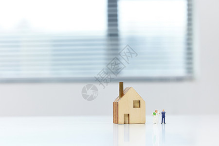 房产创意桌上的房屋模型与创意小人概念背景