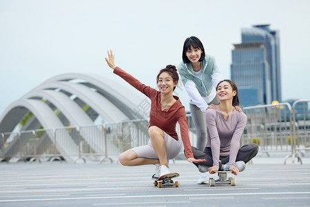 女性友人一起在户外玩滑板背景图片
