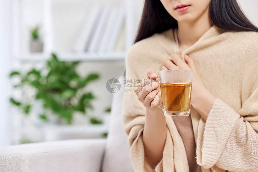 捧着姜茶裹着围巾的女性特写图片