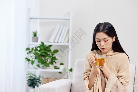 坐着喝茶的女孩冬季保暖喝姜茶的青年女性背景