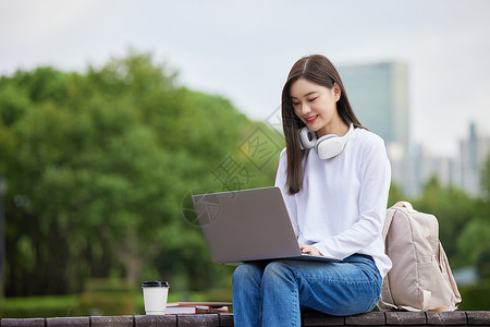 户外使用笔记本电脑的女大学生少女高清图片素材