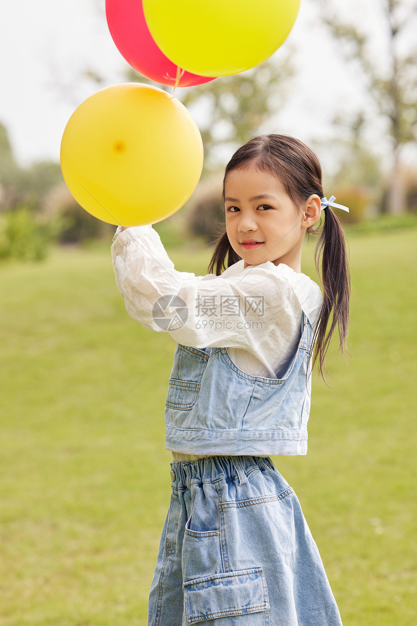 秋天室外草地上手拿气球的小女孩图片
