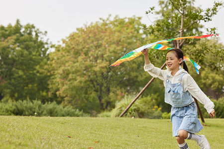 手拿风筝在草地上奔跑的小女孩图片