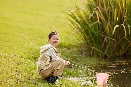 小女孩在河边使用渔网捞鱼背景