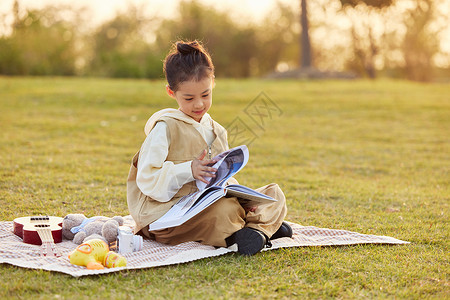 在草地上看书野餐的小女孩图片