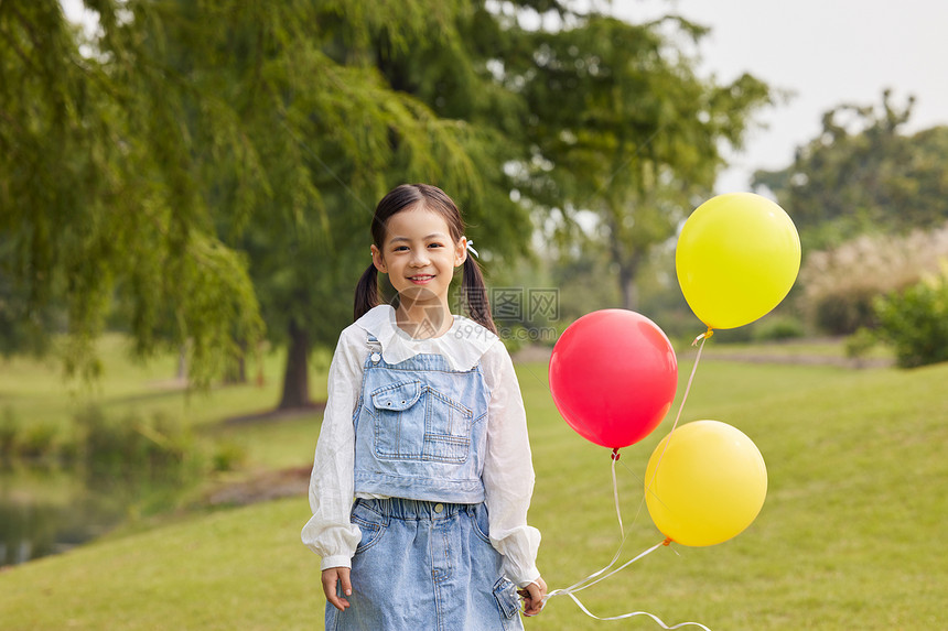 秋季户外草地上手拿气球的小女孩图片