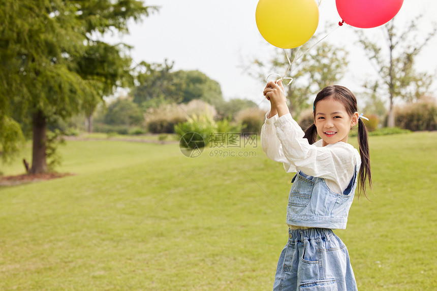 秋季草地上手拿气球的小女孩图片