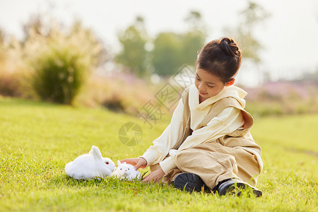 花和兔子在草地上和兔子玩耍的小女孩背景