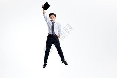 跳跃的商务男士手举平板电脑图片