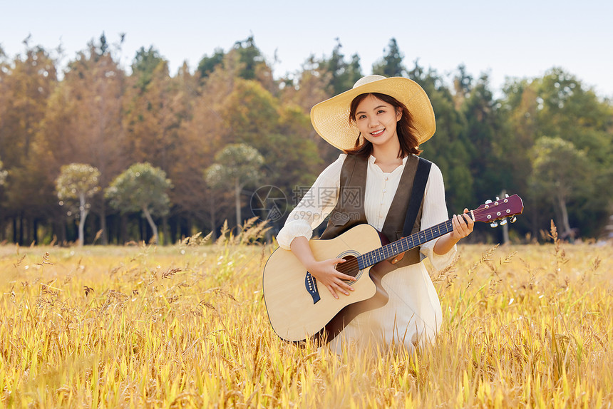 站在稻田里弹奏吉他的女性图片