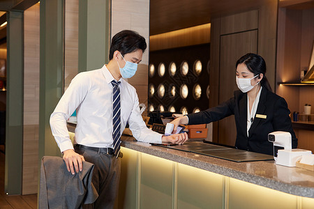 酒店前台服务人员给顾客测量体温图片