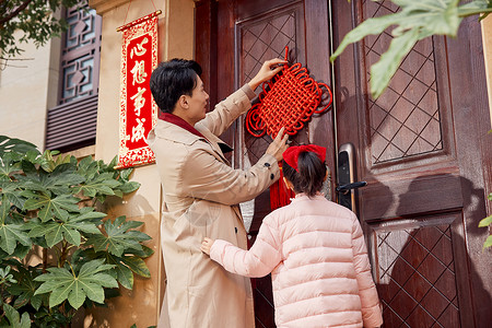 新春开门口爸爸和女儿在门口装饰中国结背景