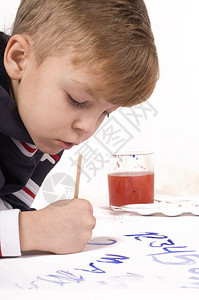 漂亮的小男孩正在纸上用水粉画图片