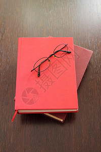眼镜和两本放在木桌上的红书图片