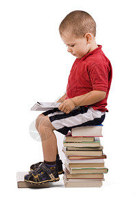 三岁男孩坐在一堆书上看书图片