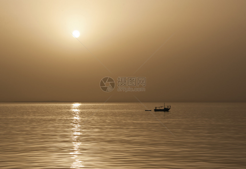 日落时独自在海上的小型传统捕鱼船图片