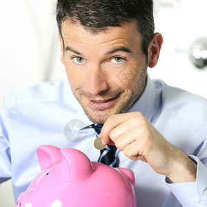 商人在小猪形状的粉红猪上垫硬币图片