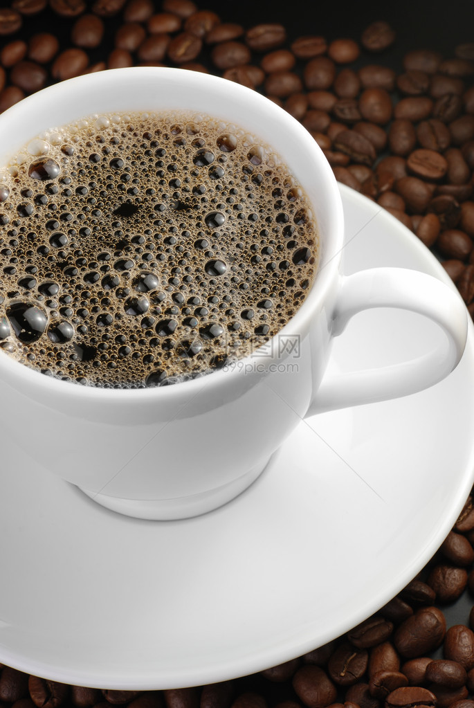 一杯含泡沫的咖啡背景有咖啡谷物和白色杯图片