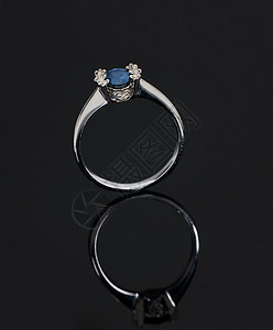 美丽的白金戒指灰色背景上的蓝色宝石图片