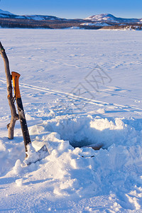 通过湖冰进行冰钓的洞图片