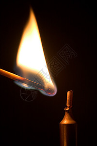 燃烧的火柴即将点燃蜡烛的照片图片