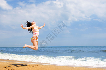 富有表现力的年轻女人在沙滩上跳跃图片